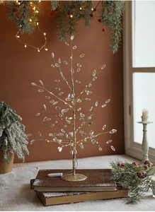 Close-up of a crystal Christmas tree ornament with warm LED lighting and golden branches