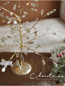 Detail of warm LED crystal Christmas tree with golden base on vintage books