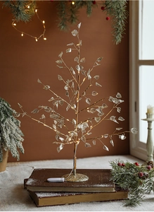 Detail of warm LED Christmas tree lamp with crystal leaves on vintage book base