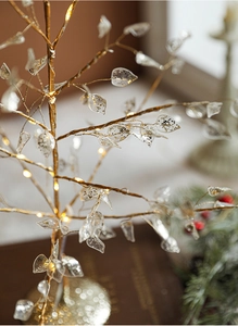 Close-up of golden branch Christmas tree with warm LED lights and crystal glitter leaves