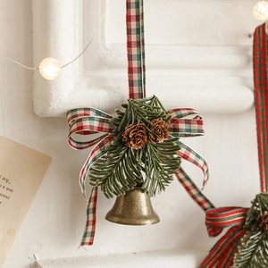 Bronze metal bell ornament with pine cones and green needles on plaid ribbon