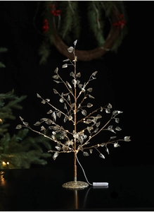 Close-up of LED glowing crystal Christmas tree with warm light and golden trunk detail