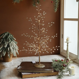 Golden crystal Christmas tree with warm LED lights on vintage books for holiday decor