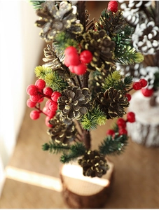 Detail of mini Christmas tree with pine cones, red berries and natural wooden base