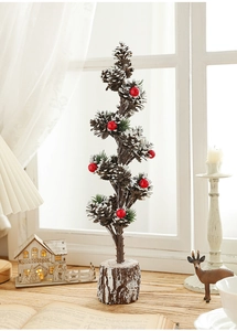 Detail of mini snowy Christmas tree with pine cones, red berries and natural wood base