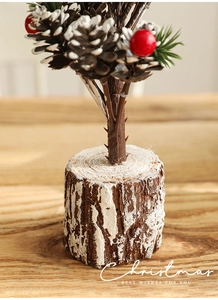 Detail of wooden base and festive red berries on a 40cm snowy mini Christmas tree