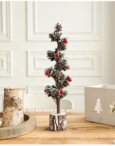 Detail showing natural pine cones and red berries on a snowy mini Christmas tree