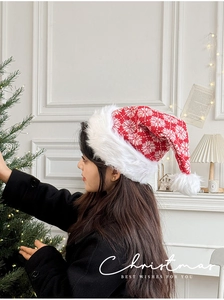 Detail of red knit Christmas hat with white snowflake patterns and plush pom-pom
