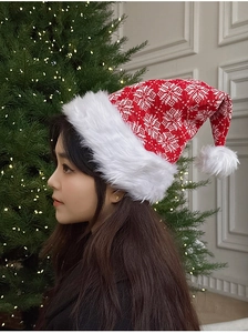 Side view of a red knitted Christmas hat with white snowflake patterns and plush fur trim