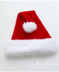 Close-up of classic plush red Christmas hat with white faux fur trim and fluffy pompom