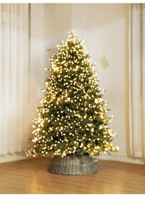 Detail of pre-lit Christmas tree needles with warm LED lights and woven basket base
