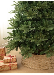 Detail of luxury glowing Christmas tree with warm LED lights and woven tree collar base