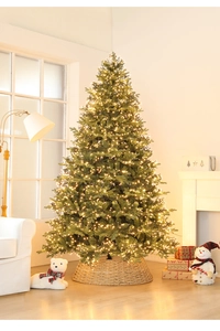 Close-up of a dense artificial Christmas tree with warm LED lights and a rattan base