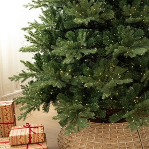 Lush pre-lit Christmas tree with warm white LED lights and woven brown tree collar