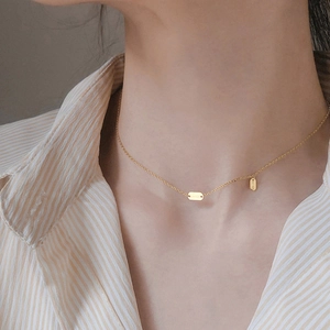 Close-up of a gold 925 sterling silver necklace with Lucky engraved vertical pendants