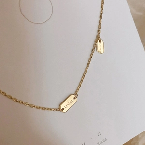 Detailed close-up of a 925 silver golden chain necklace with engraved Lucky oval charms