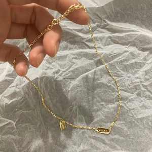 Close-up of golden lucky necklace featuring dual rectangular pendants on a fine chain