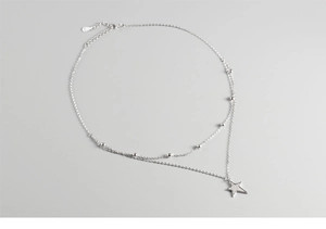 Macro shot of double-layered S925 sterling silver star pendant necklace and small round beads