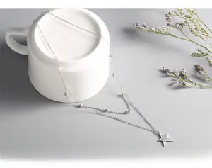 Close-up of double layer silver star pendant necklace wrapped on white ceramic mug