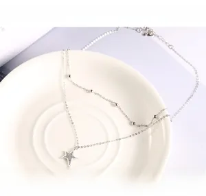 Macro detail of a double-layered 925 silver necklace with star pendant and bead chain