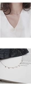 Detailed view of silver minimalist necklace with small cross charms on model and background