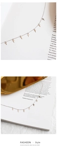 Detailed view of silver minimalist cross pendant necklace on stylish prop magazines