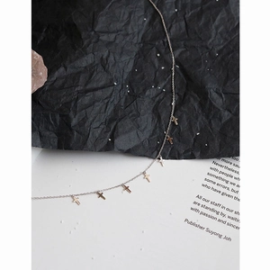 Minimalist silver cross pendant necklace displayed on a textured aesthetic background