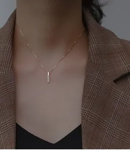 Dettaglio di una collana con ciondolo a barra verticale in oro rosa con piccole pietre su modella