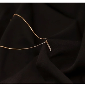 Dettaglio ravvicinato di una collana con ciondolo a barra verticale in oro rosa e zirconi
