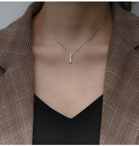 Collana barretta minimalista in argento S925 con zirconi su un blazer a scacchi