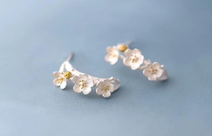 Macro detail of 925 sterling silver cherry blossom earrings with golden pistil accents