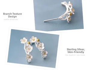 Detailed close-up showing cherry blossom floral textures and branch design on silver earrings