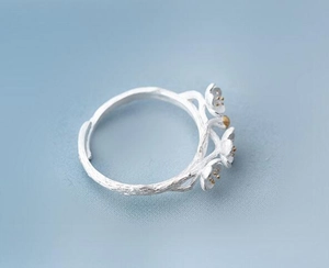 Close-up of adjustable cherry blossom ring with textured silver branches and golden pistils