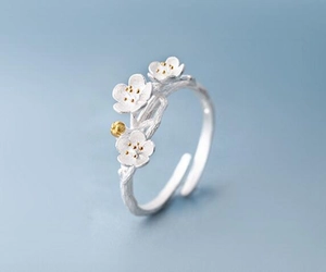 Detailed macro view of 925 silver cherry blossom ring with golden stamen and branch texture