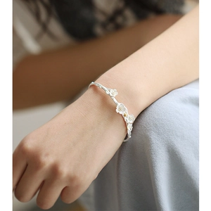 Detail of elegant 925 silver cherry blossom open cuff bracelet on female wrist