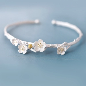 Macro detail of silver cherry blossom open bangle with matte petals and gold stamens