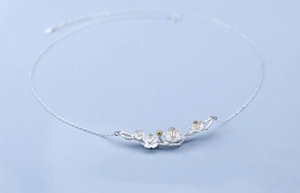 Macro detail of 925 sterling silver cherry blossom necklace with matte flower petals