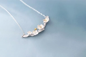 Detail of S925 silver flower branch necklace with brushed texture and gold accents