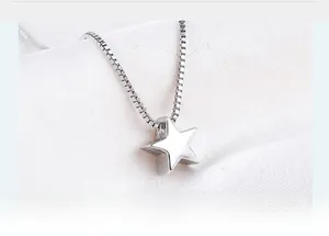Macro detail of a minimalist S925 sterling silver star pendant on a box chain necklace