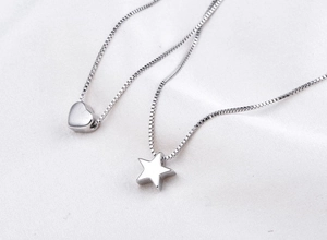 Close-up of minimalist S925 sterling silver necklaces with heart and star pendants