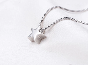 Close-up of a 925 silver star pendant necklace on a delicate white textured background