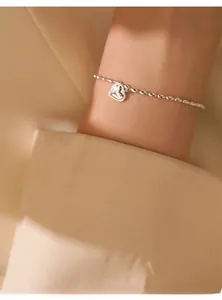 Macro shot of S925 sterling silver rice bead bracelet with heart charm on wrist