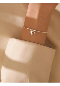 Close-up of S925 sterling silver rice bead bracelet with heart pendant on wrist