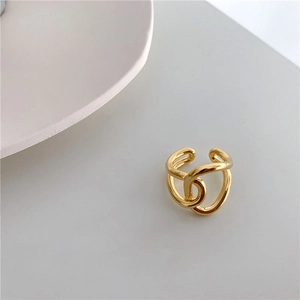 Close-up of a gold minimalist open ring featuring intertwined wavy lines and mirror finish