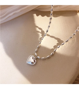 Macro detail of silver heart pendant with beaded edge and oval rice bead chain links