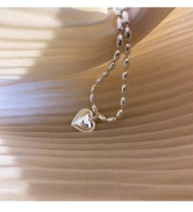 Macro shot of S925 sterling silver rice bead bracelet with textured heart pendant