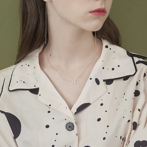 Detail of four-pointed star necklace and linear drop earrings worn by model