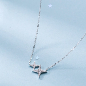 Detail of silver star pendant necklace featuring layered four-pointed stars with zircon
