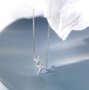 Macro shot of silver cross star necklace with zircon pavé details in minimalist style