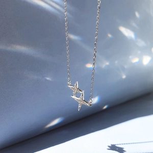 Elegant four-pointed star necklace with sparkling cubic zirconia on light blue silk background